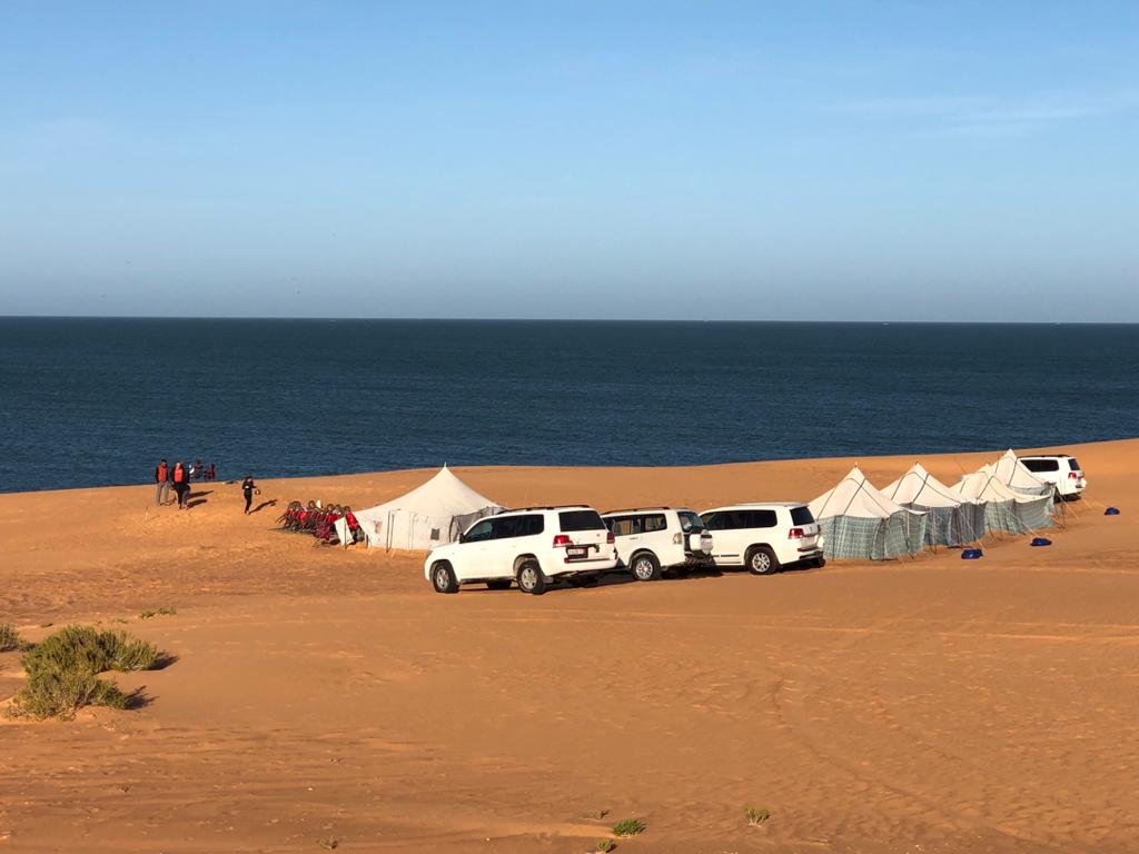 Fleet vehicles make a line next to function tents along the Mauritania beach