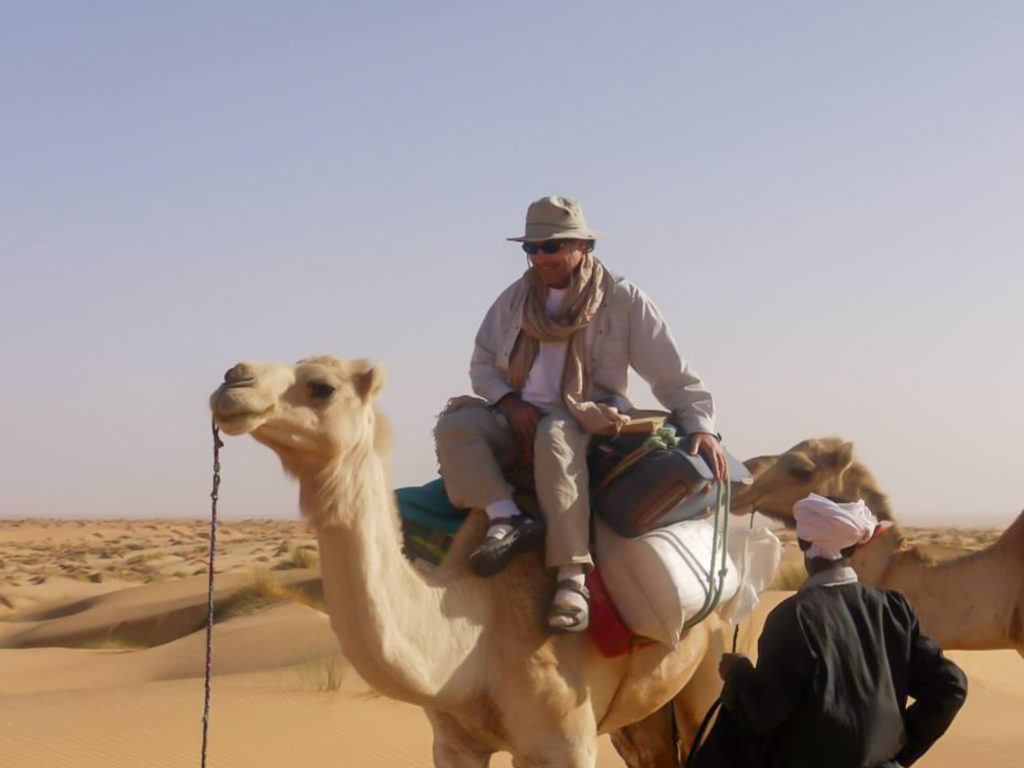 A man rides a camel also carrying many luggage items